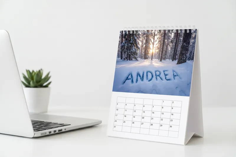 Portrait desk calendar with a photo of a snowy mountain and a name carved into the snow